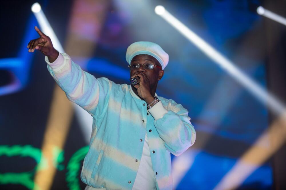 A man in a hat and jacket performs on stage.